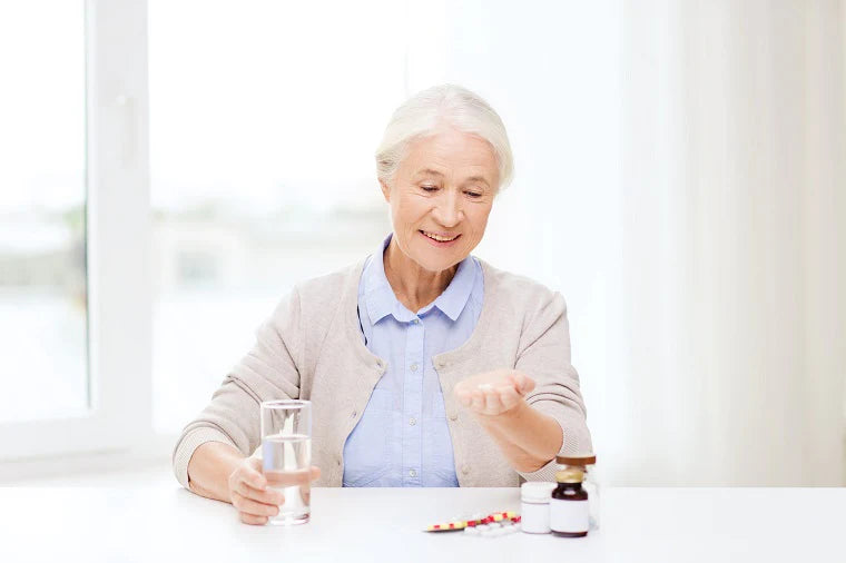 A pleasant older lady holds a glass of water and prepares to take her medications. 