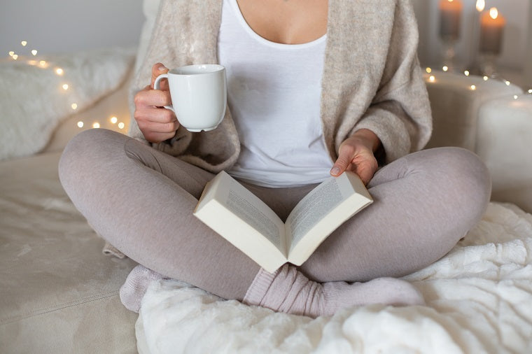 Woman in cozy attire, reading a good book which is one of the steps to help building emotional resilience