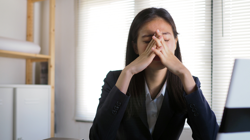 Employee suffering from migraine at their desk