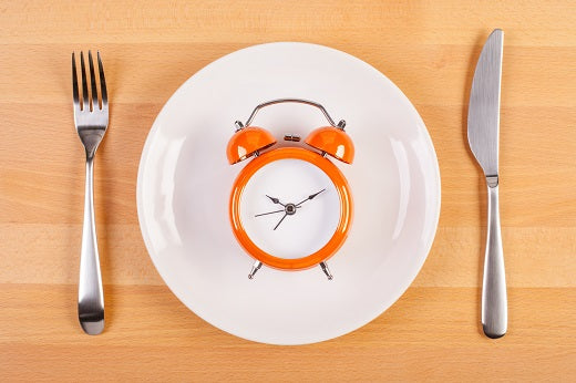 A table setting with a clock sitting on the plate