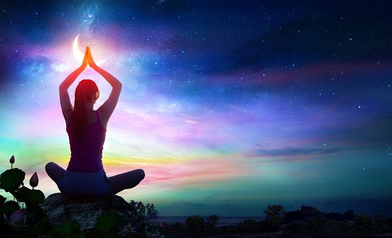A woman does a yoga pose with the Northern Lights in the background. 