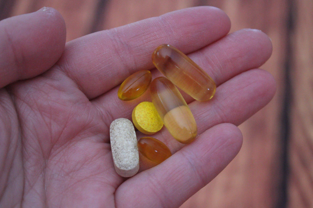 an assortment of vitamins and supplements  are being held in a person's palm